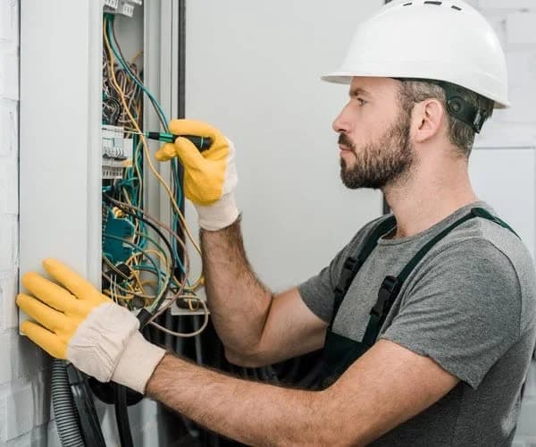 Electrician in a hard hat working on a consumer unit