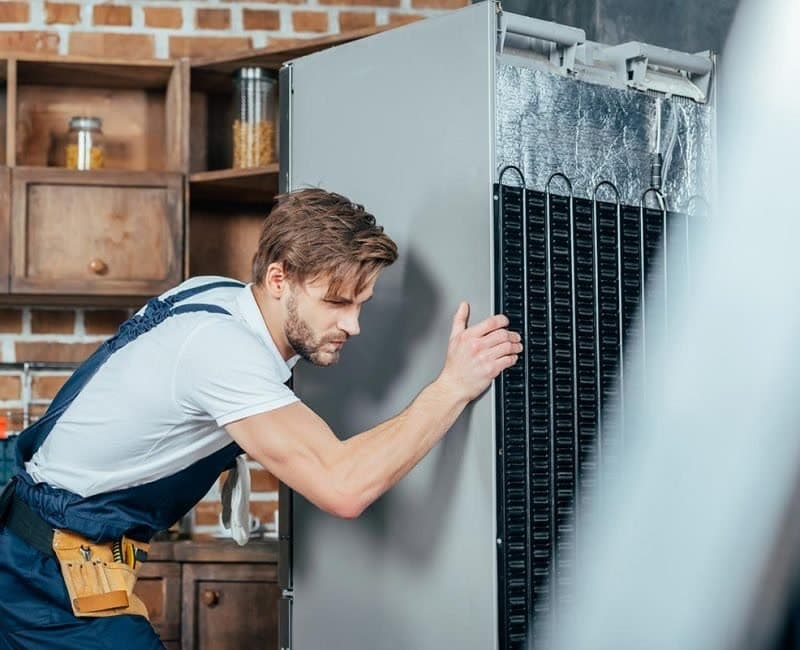 Kitchen fitter moving an appliance into place during an installation