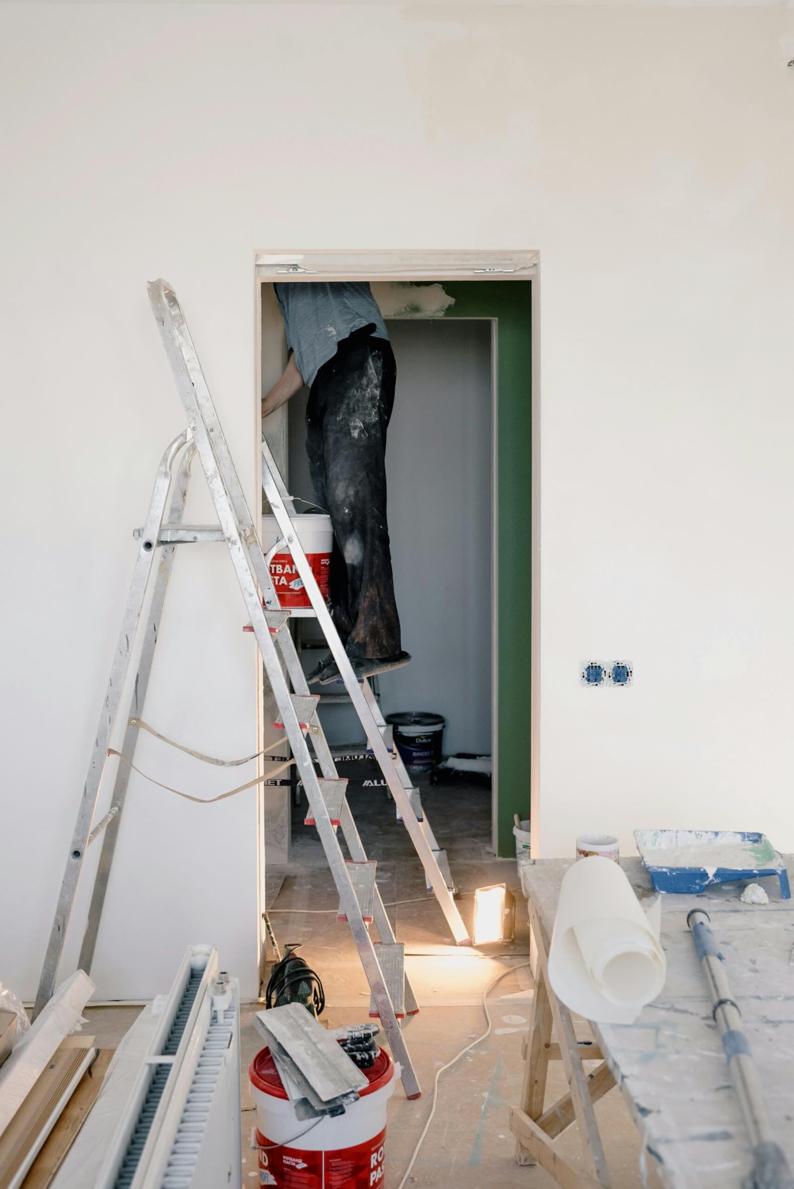Decorator preparing a rental property on a step ladder